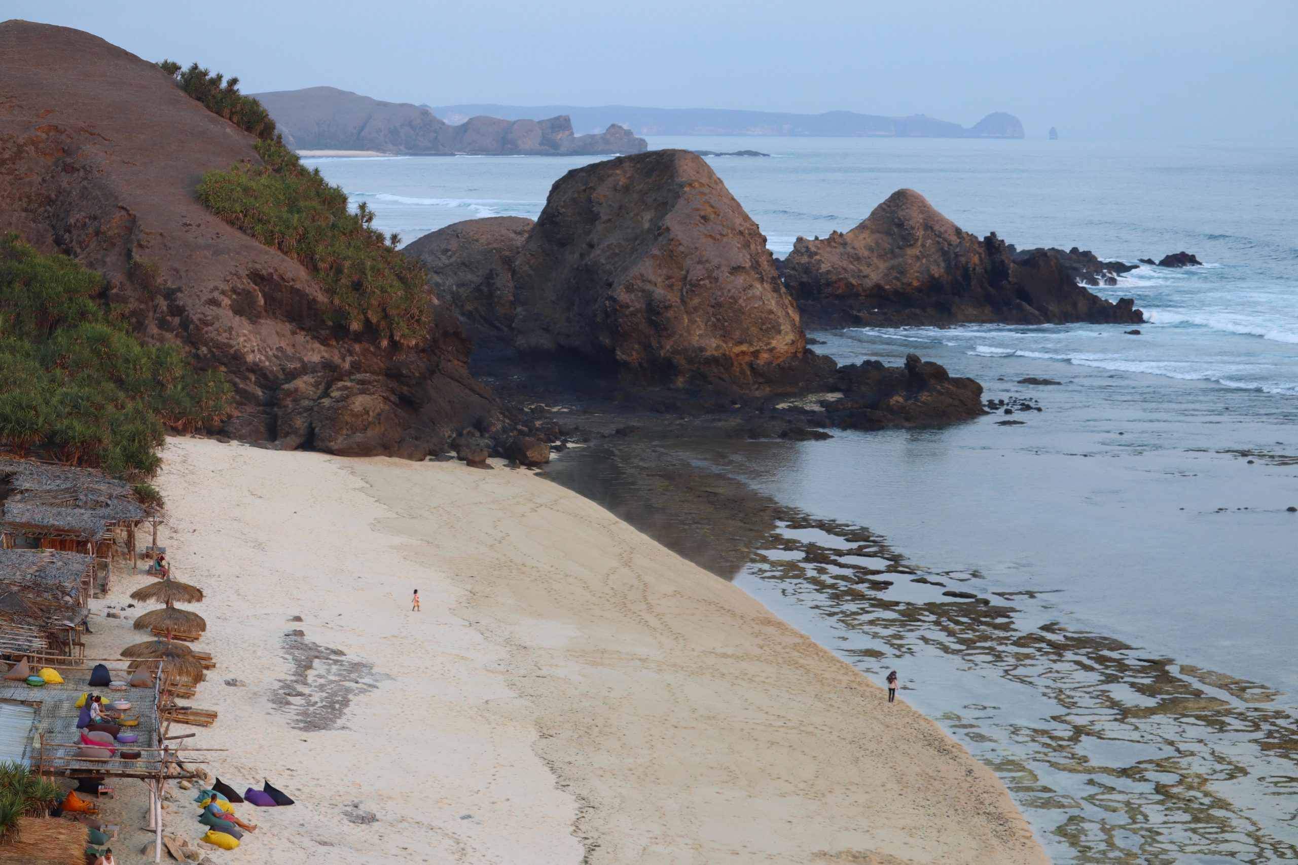 Ruhiger Sandstrand von Seger Beach auf Lombok mit markanten Felsformationen und Blick auf das Meer.