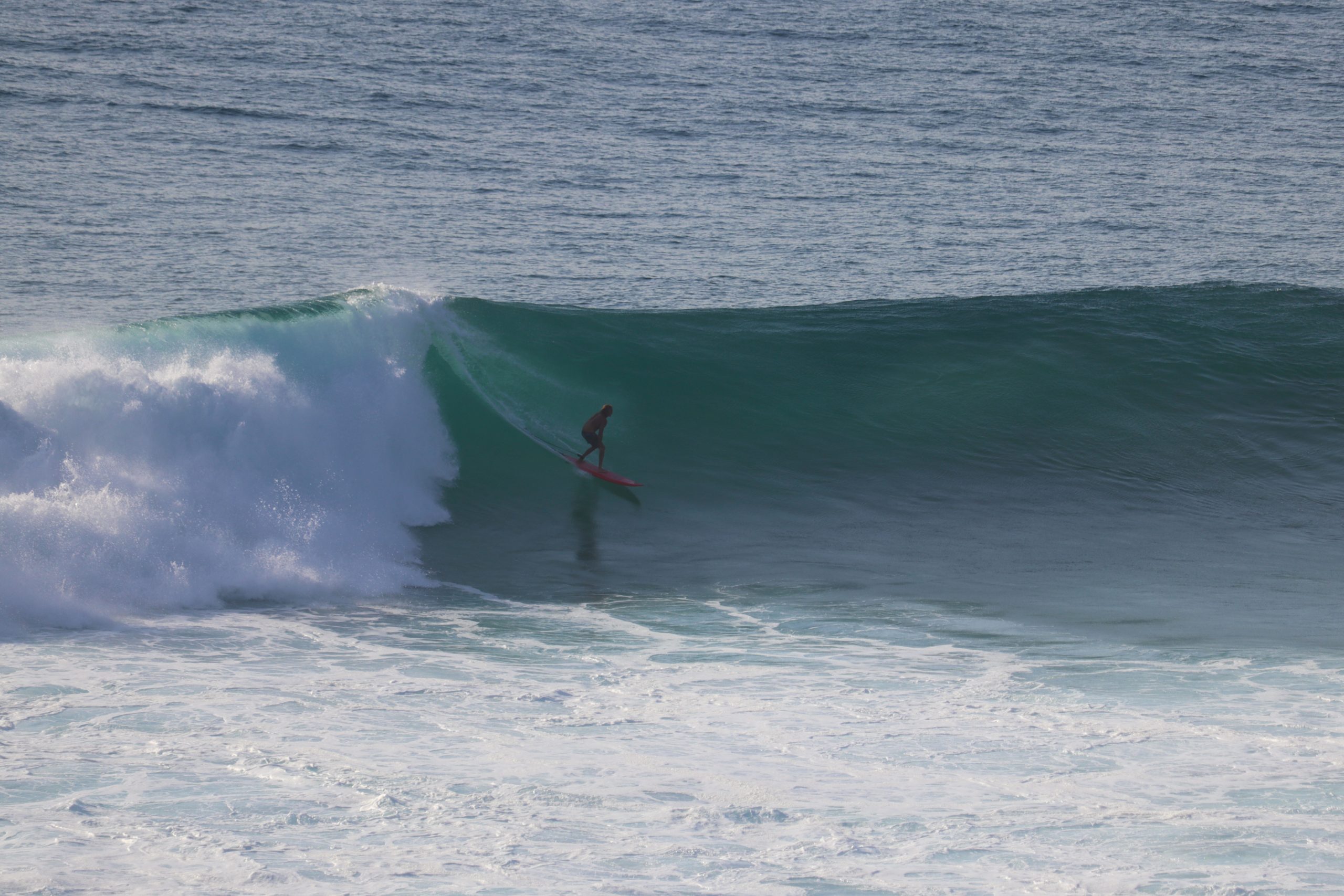 Surfer reitet eine gewaltige Welle am weltberühmten Riff-Break von Uluwatu auf Bali.